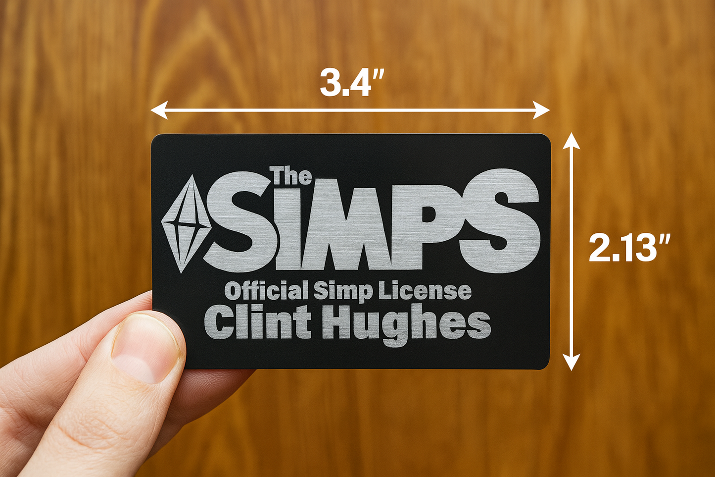 Hand holding metal Simp license with dimensions labeled on a wooden background