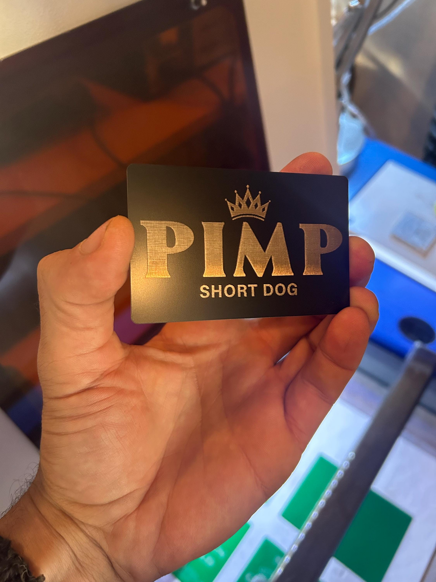 Hand holding a laser engraved metal black/silver personalized gag gift card with 'PIMP" and customized text and crown logo.