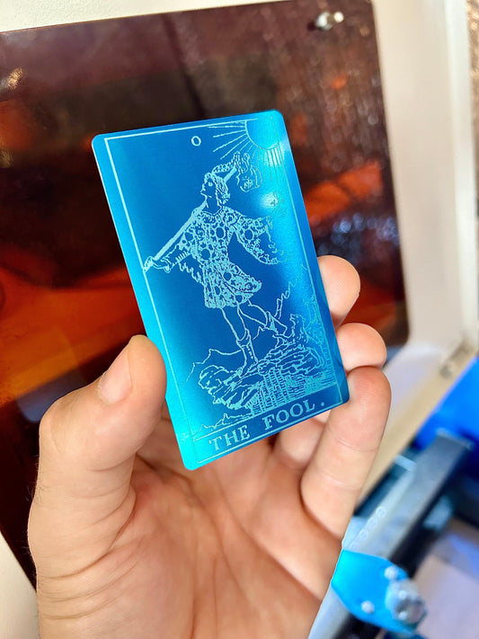 Metal tarot card with "The Fool" laser engraving in blue/silver anodized aluminum