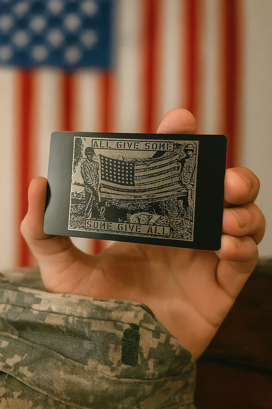 Person holding a metal commemorative keepsake card with 'All Give Some, Some Give All' text in front of an American flag.