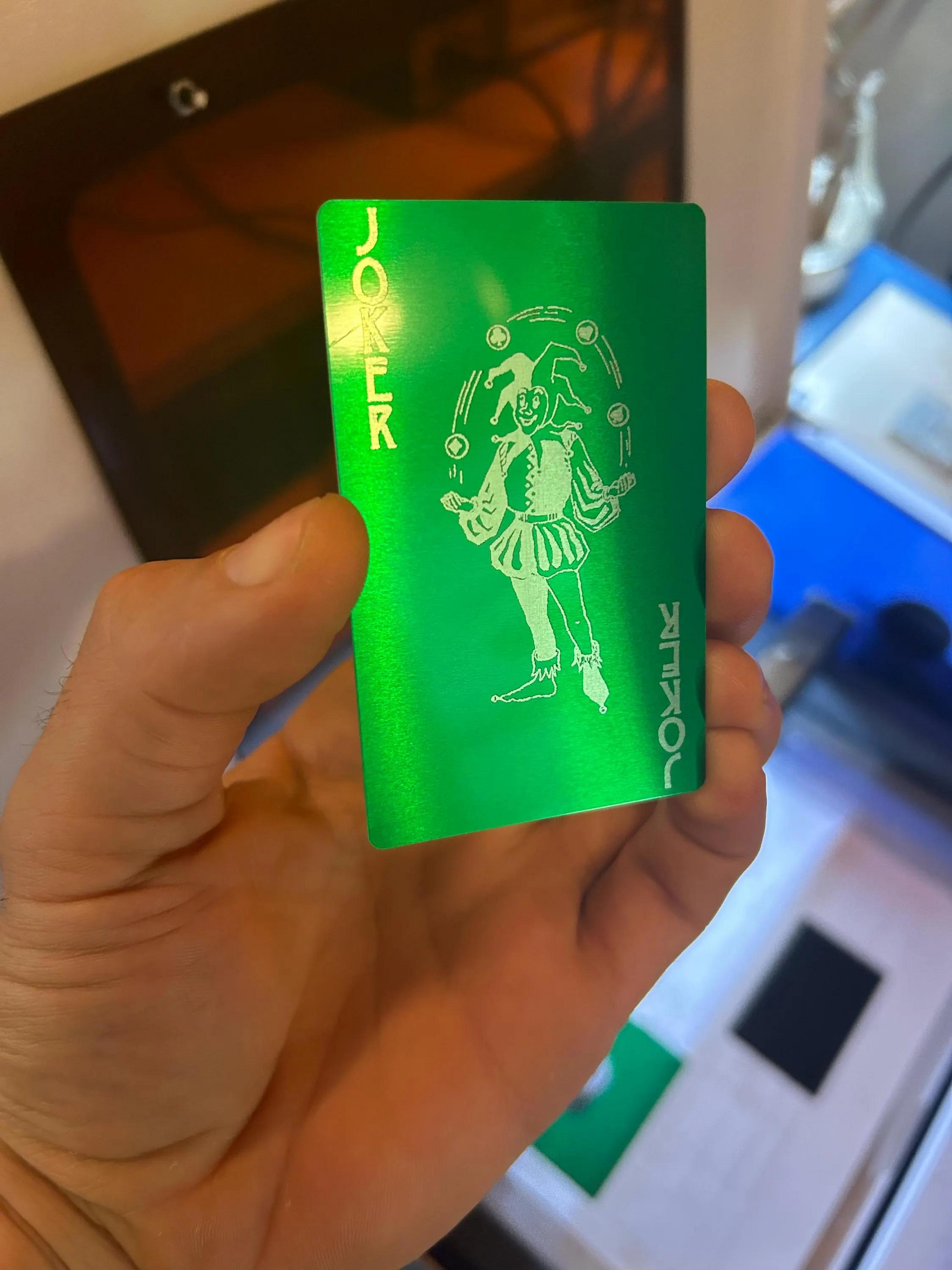 Green card with a jester design held by a hand, with a blurred background