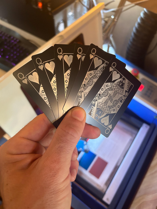 Hand holding a set of metal queen poker cards with a blurred background