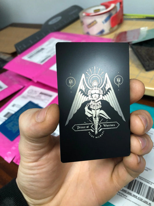 Black card with white design held by a hand against a blurred background of shipping parcels