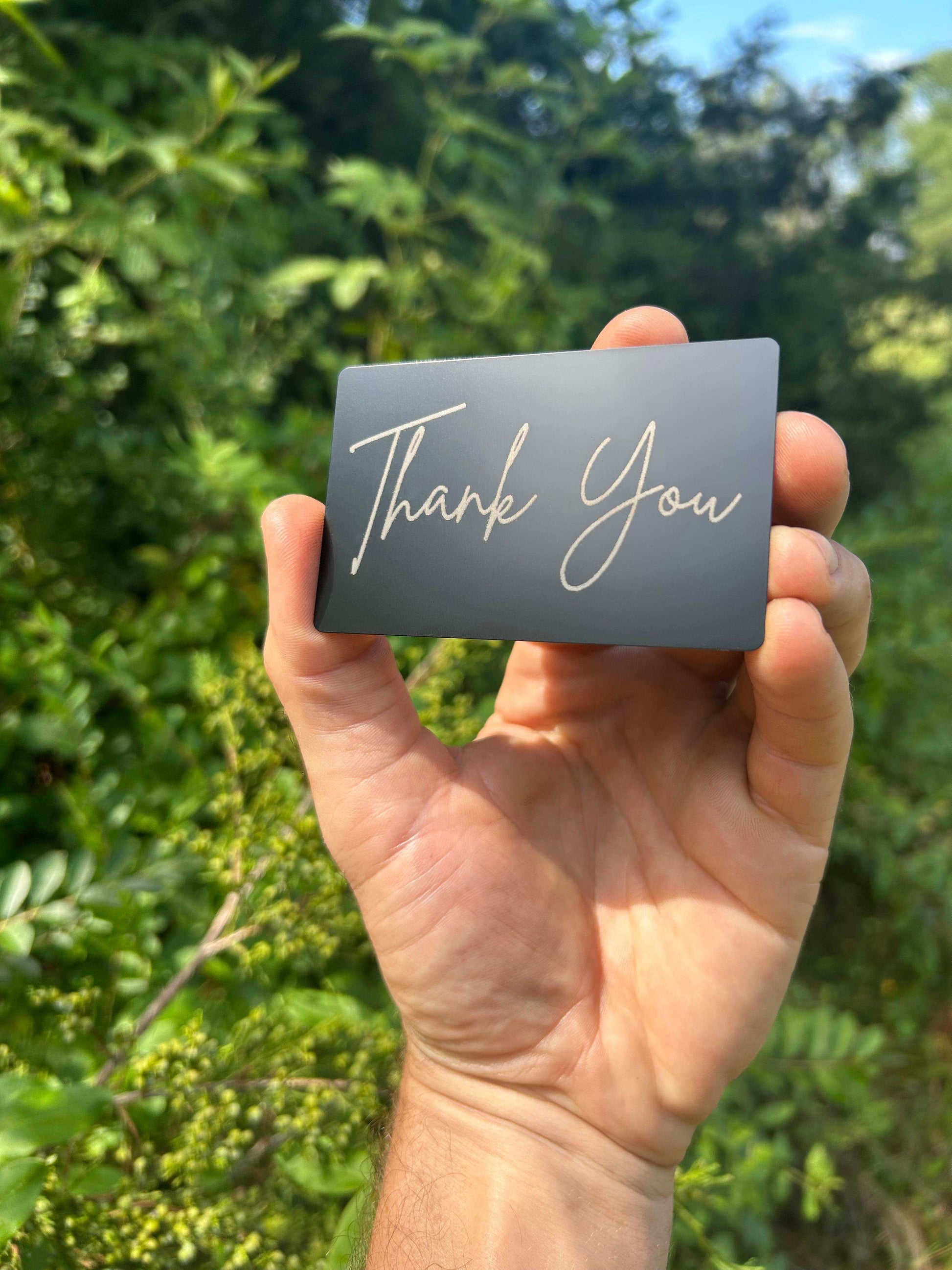 custom metal business card that has "thank you" engraved in silver on a matte black keepsake greeting card