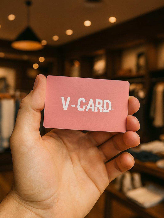 Hand holding a pink card with 'V-CARD' text in a blurred indoor setting