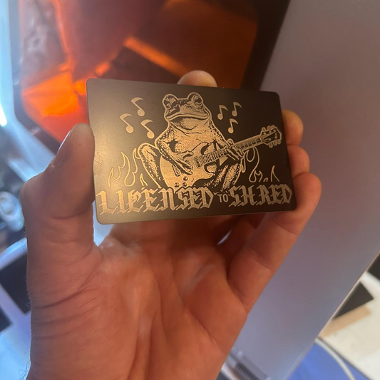 Hand holding a metal laser engraved gift card licensed to shred sarcastic funny frog design and text.