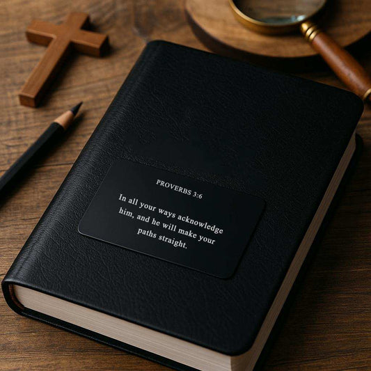 Black notebook with Proverbs 3:6 quote on a wooden surface with a cross and magnifying glass.