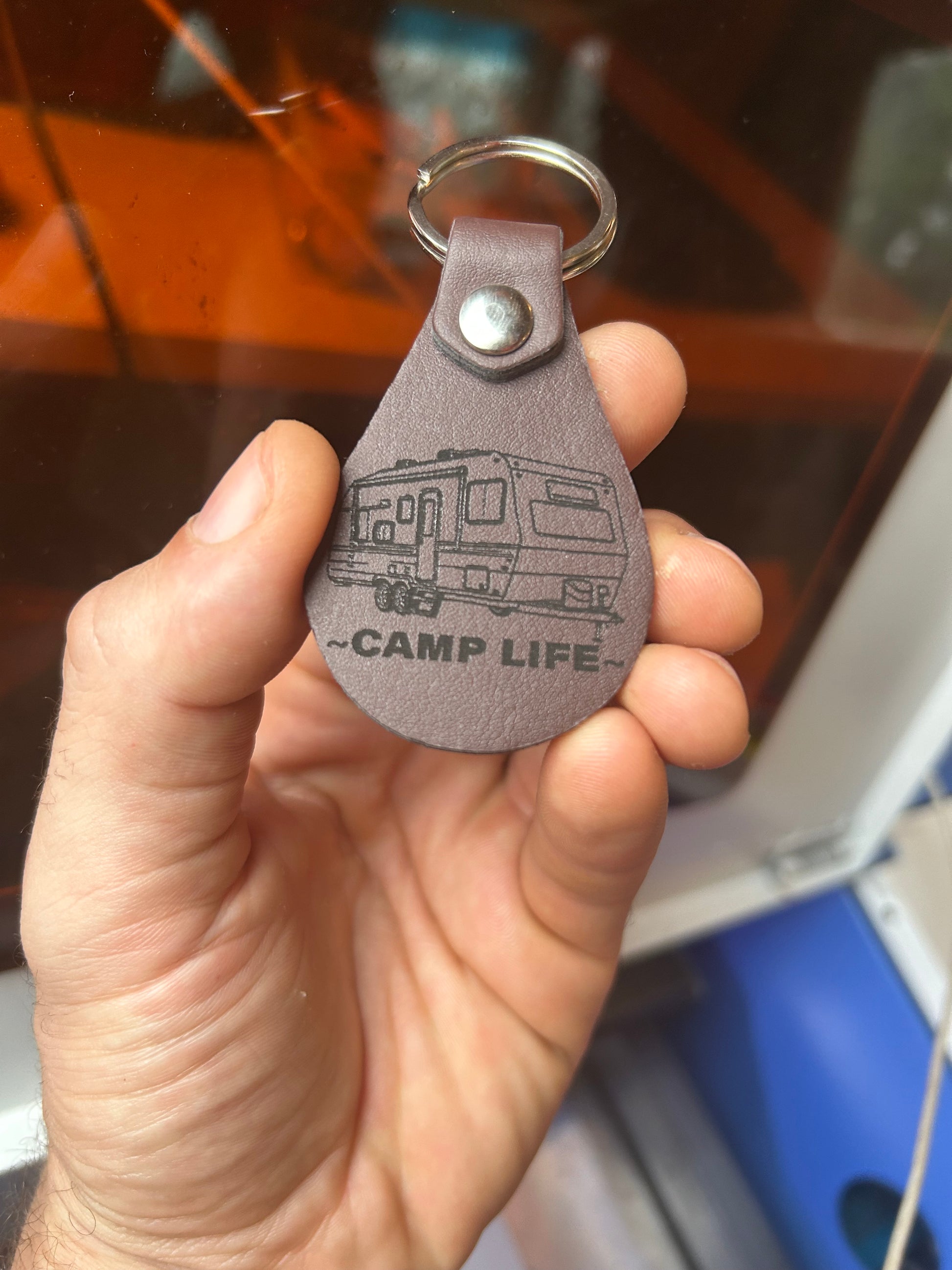Hand holding a brown leather keychain with a RV camper and the words 'CAMP LIFE' laser engraved