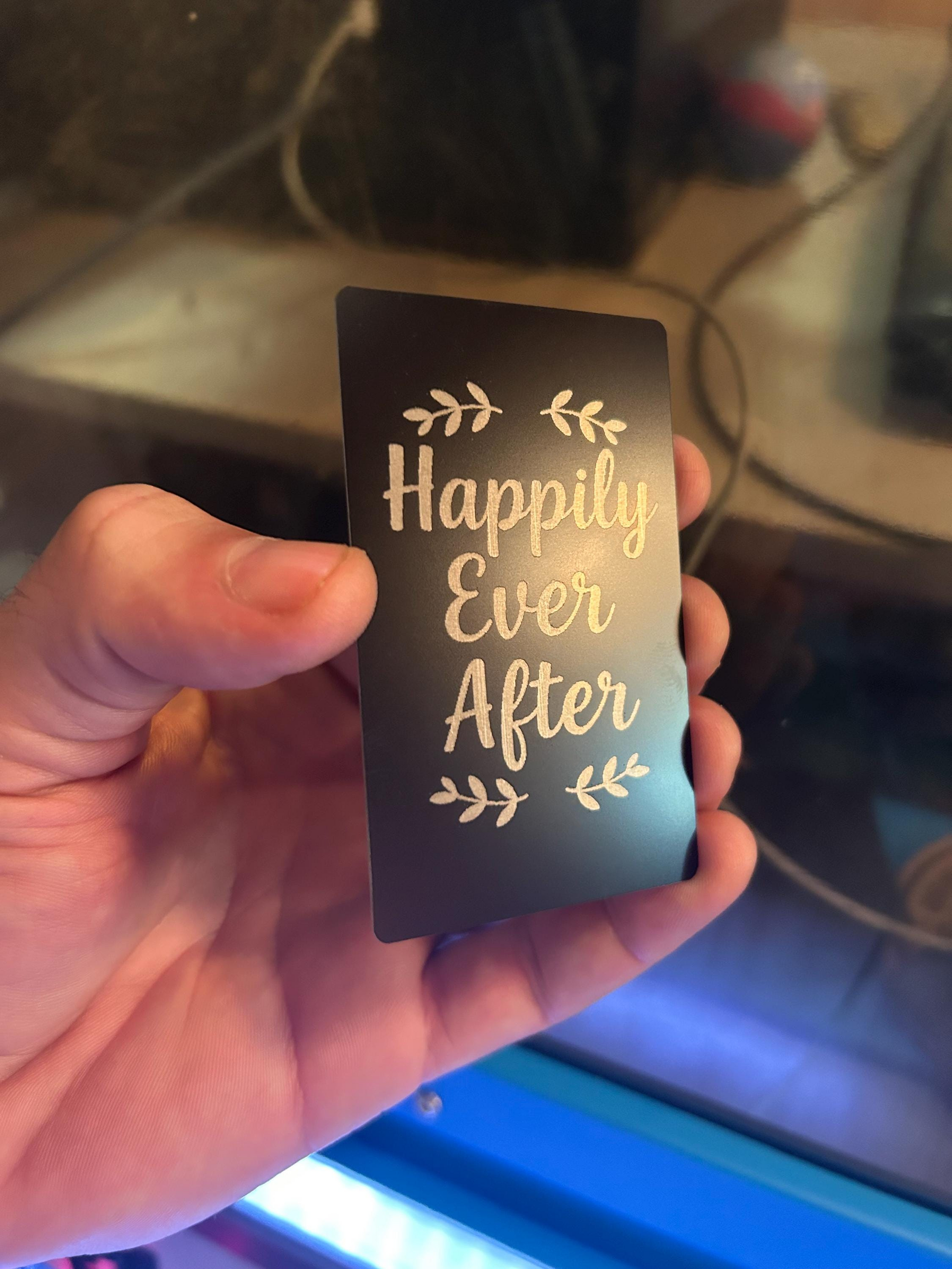 Close-up of engraved anodized aluminum wedding card reading “Happily Ever After” in elegant typography