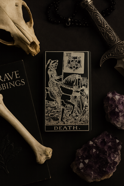 Metal black/silver Tarot card labeled 'Death' surrounded by a skull, dagger, and amethyst crystals on a dark surface.