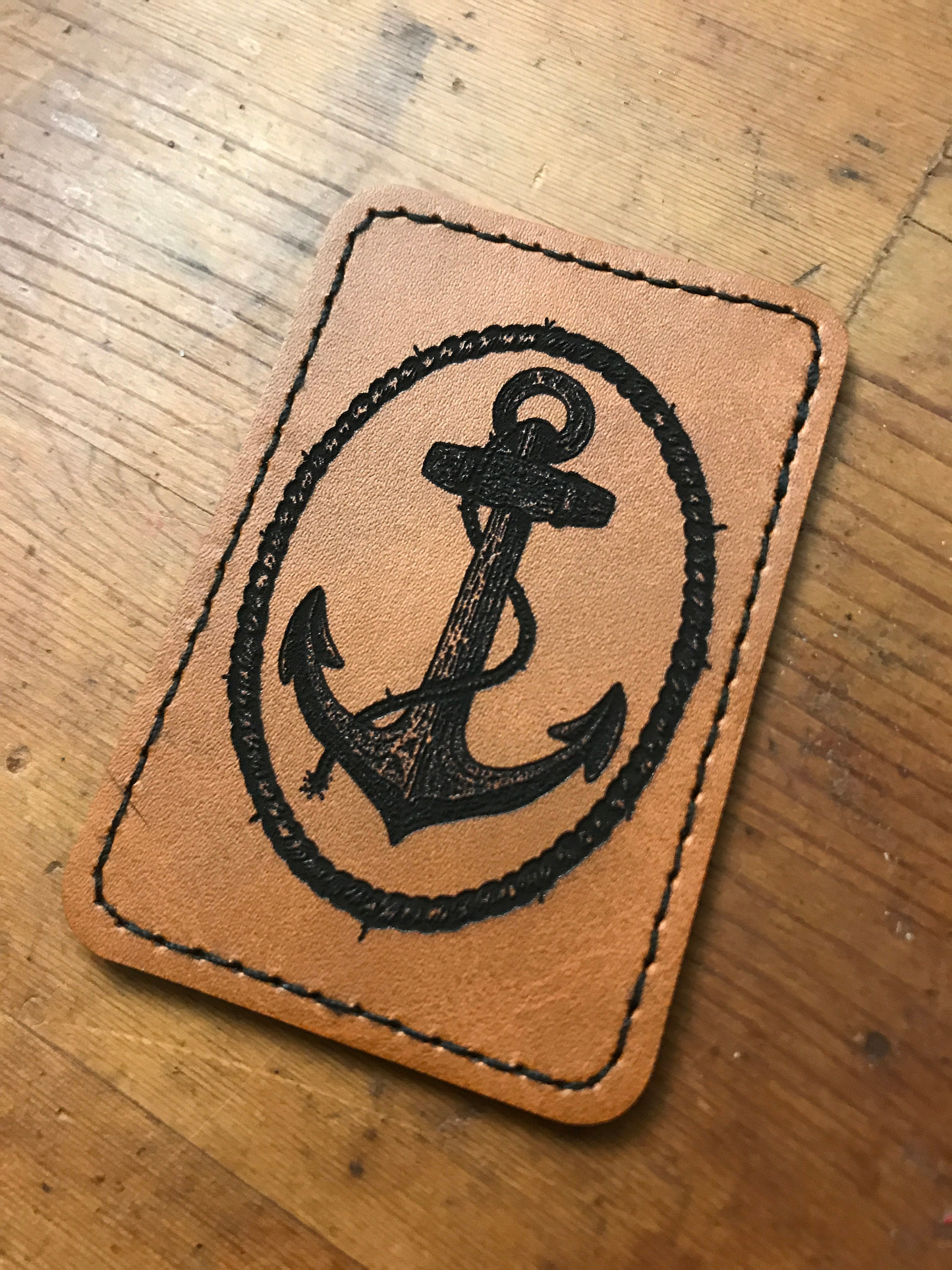 Leather patch with an anchor design on a wooden surface