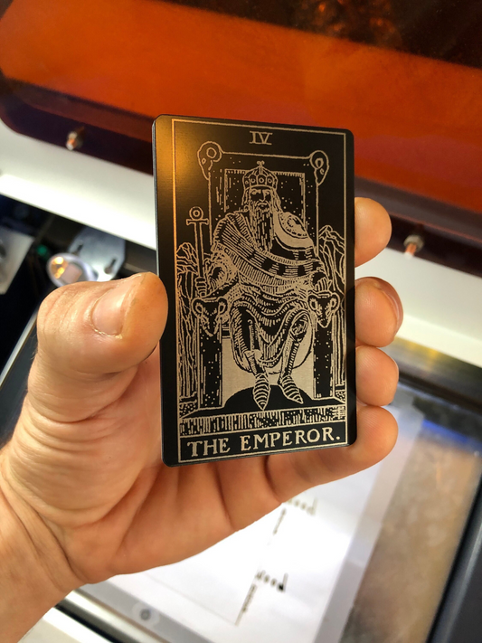 Card featuring 'The Emperor' from a metal tarot deck held in a hand.