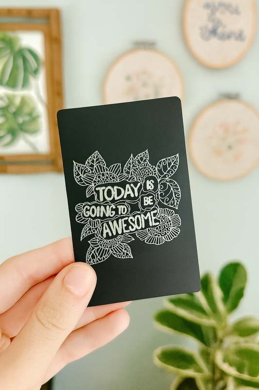 Person holding a laser engraved inspirational gift card in black and silver with floral design and “Today Is Going To Be Awesome” quote
