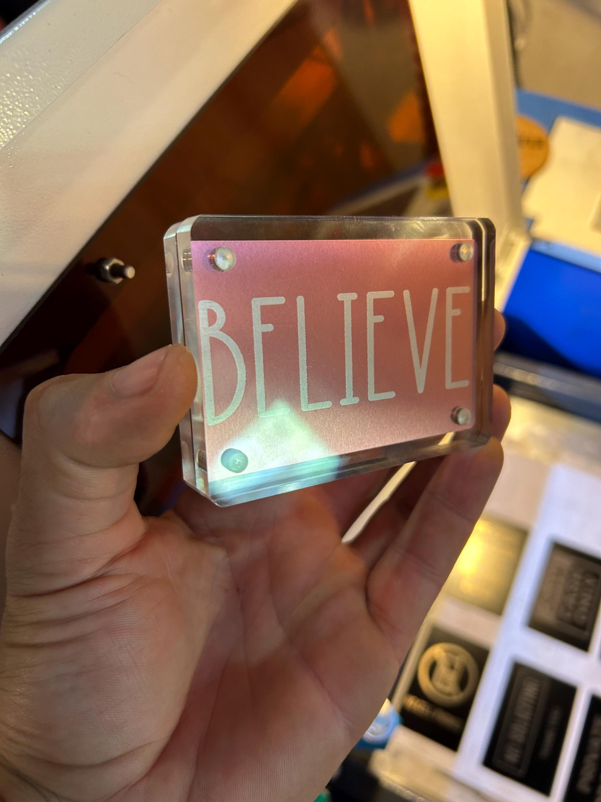 Rose gold inspirational keepsake card with “BELIEVE” message, demonstrated in acrylic display