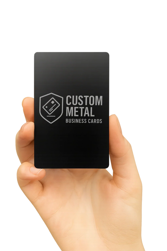 Hand holding a black card with 'Custom Metal Business Cards' text and logo on a white background
