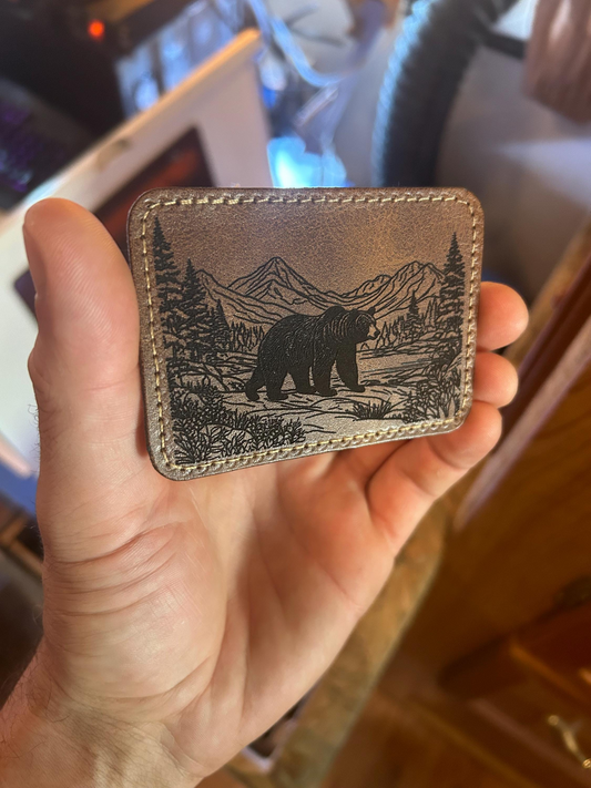 Dark brown leather patch with a detailed laser engraving of a brown bear and nature design