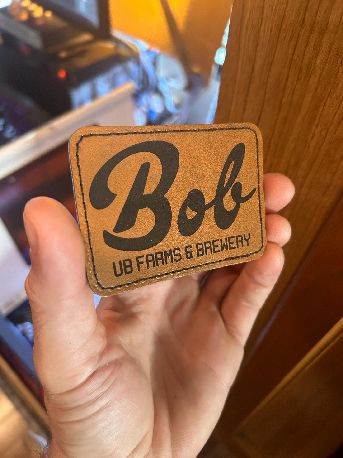 Brown leather patch with customized 'Bob UB Farms & Brewery' text