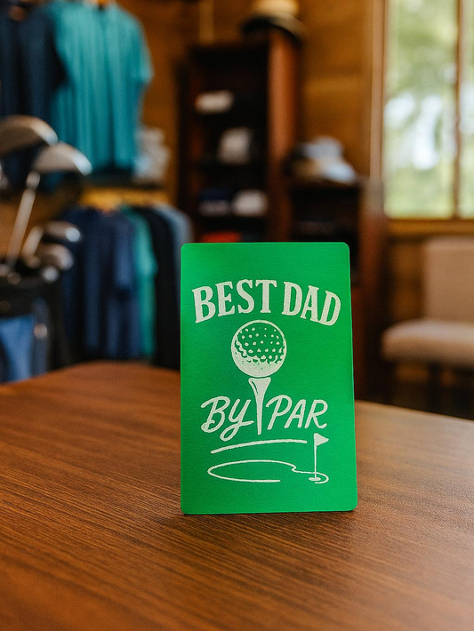 Green metal keepsake card with 'Best Dad by Par' text engraved with golf design on a wooden surface.