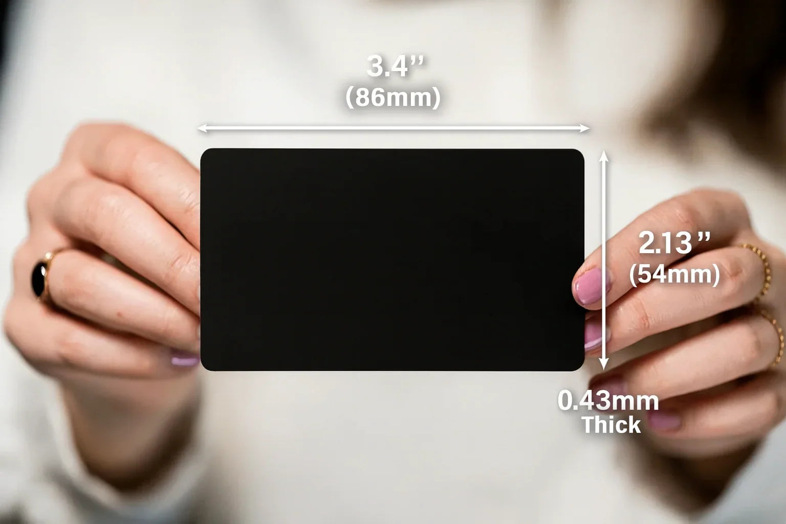 Black card held by hands with measurements indicated