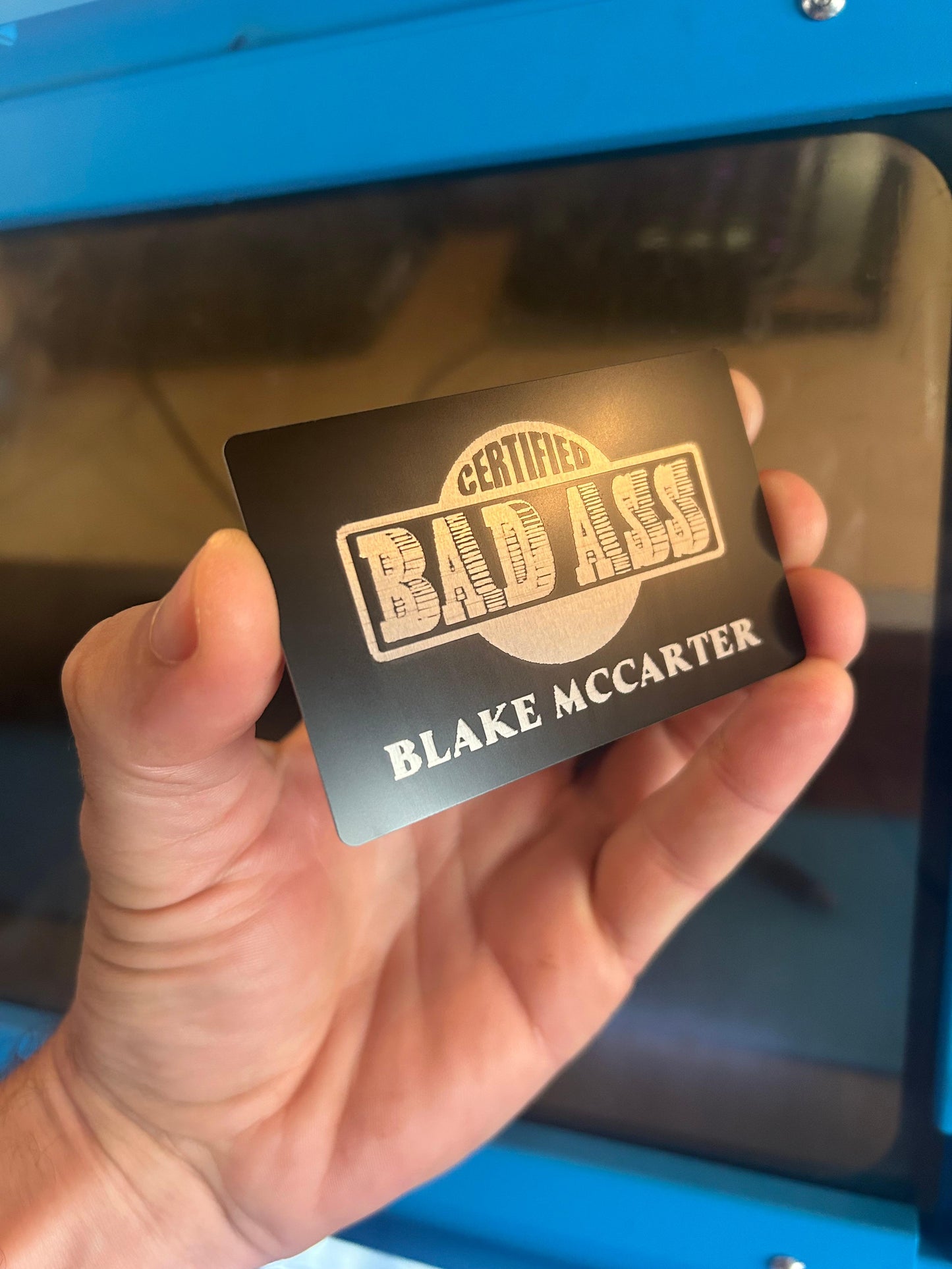 Laser engraved metal 'Certified BadAss' card with personalized name engraving in black/silver