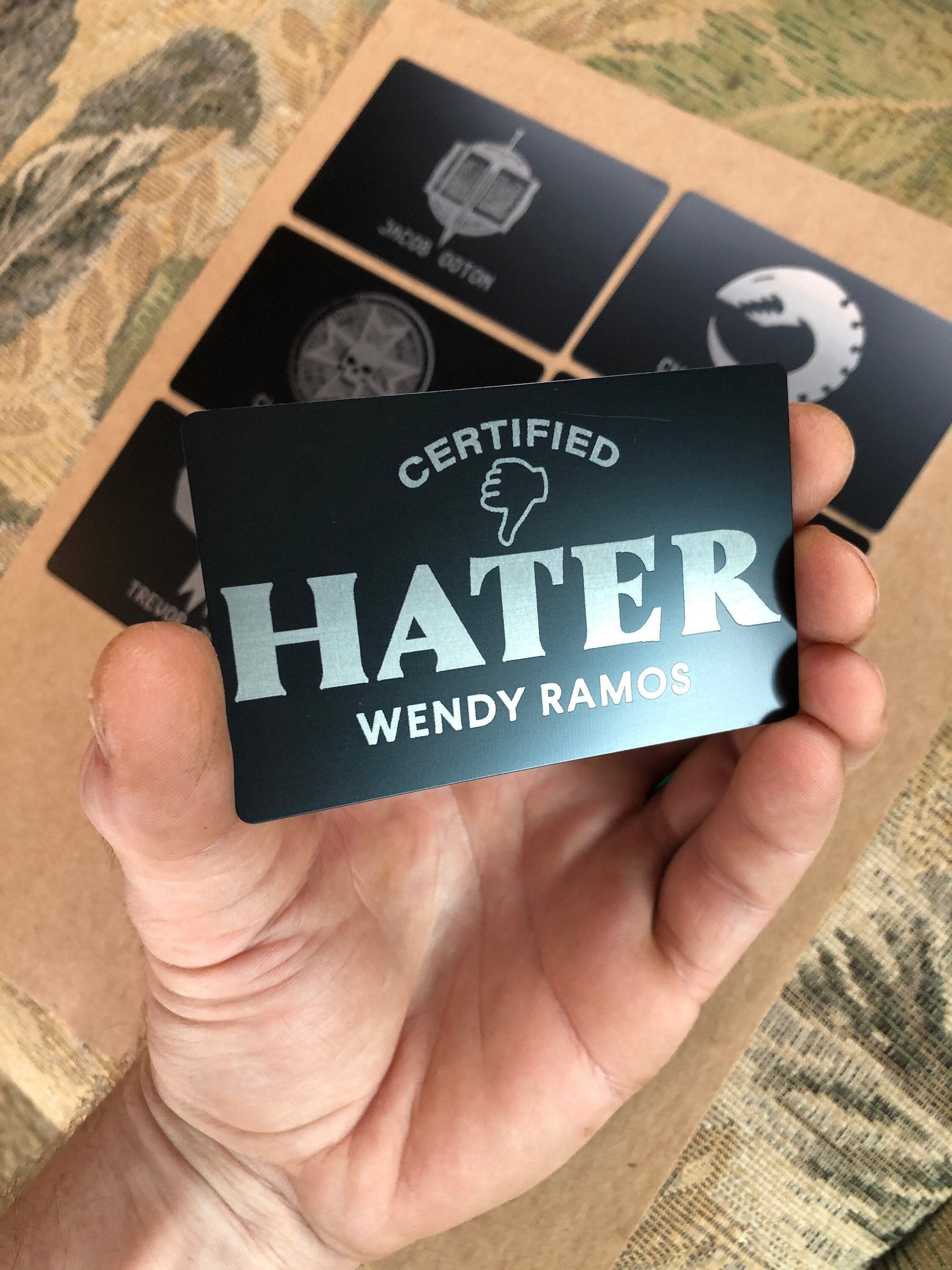 Laser engraved metal keepsake card with Certified Hater artwork and personalized name engraved below