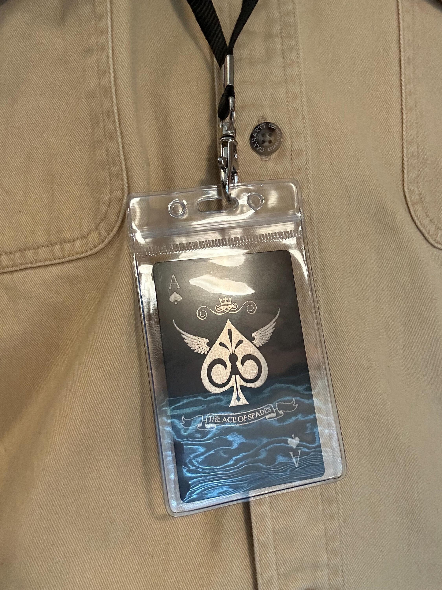 Clear badge holder with card attached to a beige jacket