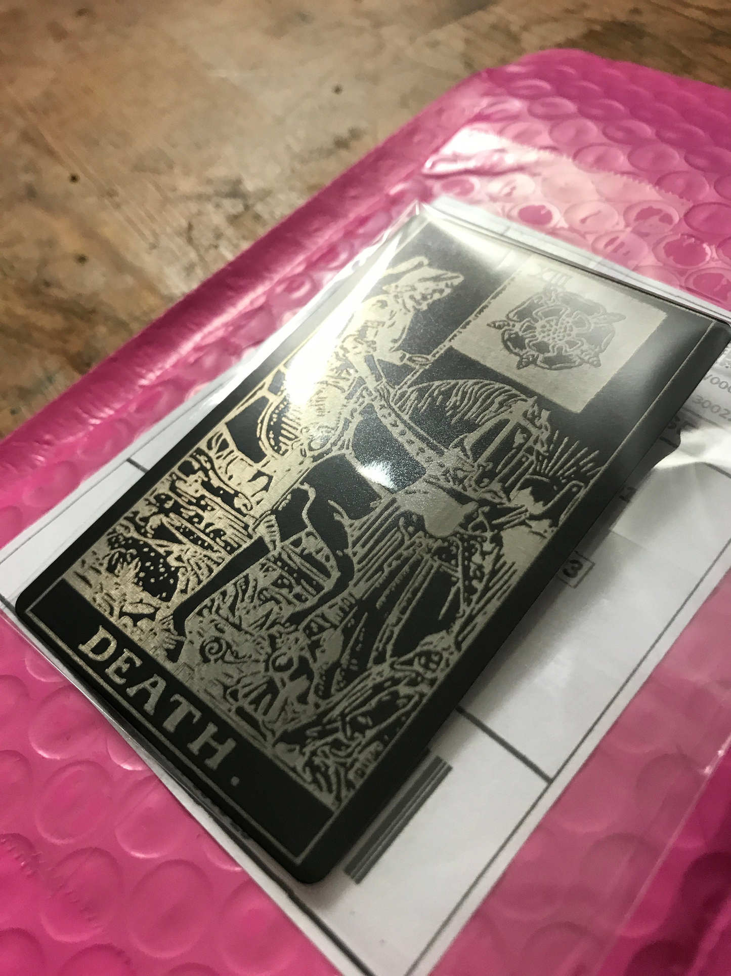 Metal Tarot Card with 'DEATH' from a tarot deck on a pink mailer