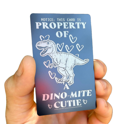 Card with a dinosaur illustration and text held by a hand on a white background