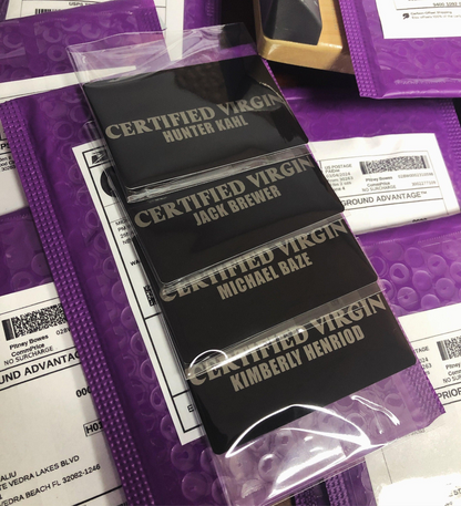 multiple certified virgin laser engraved metal gag gift cards, with custom names against a background of product mailers