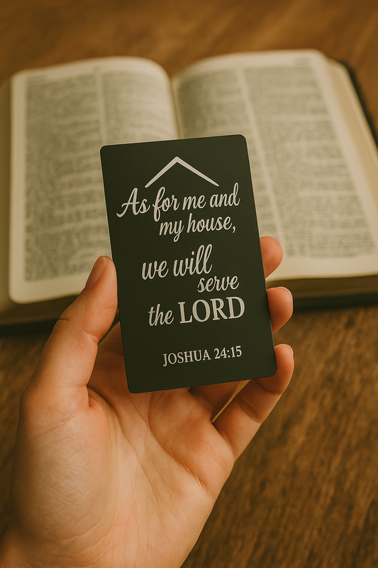 Hand holding a metal keepsake wallet insert with 'As for me and my house, we will serve the LORD' against an open Bible background