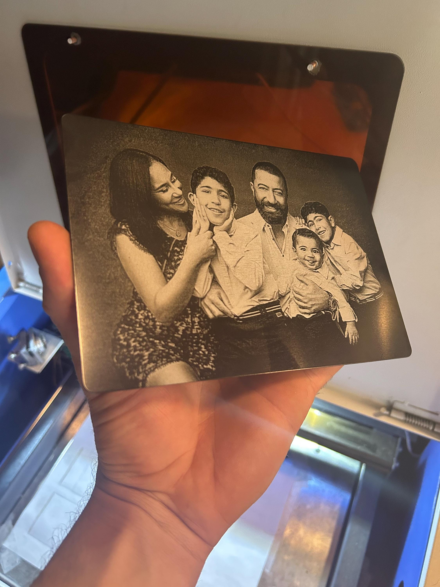 Metal engraved photograph of a family held by a hand