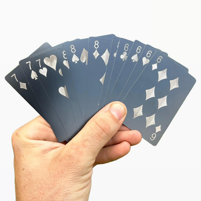 Hand holding a set of metal playing gift cards against a white background