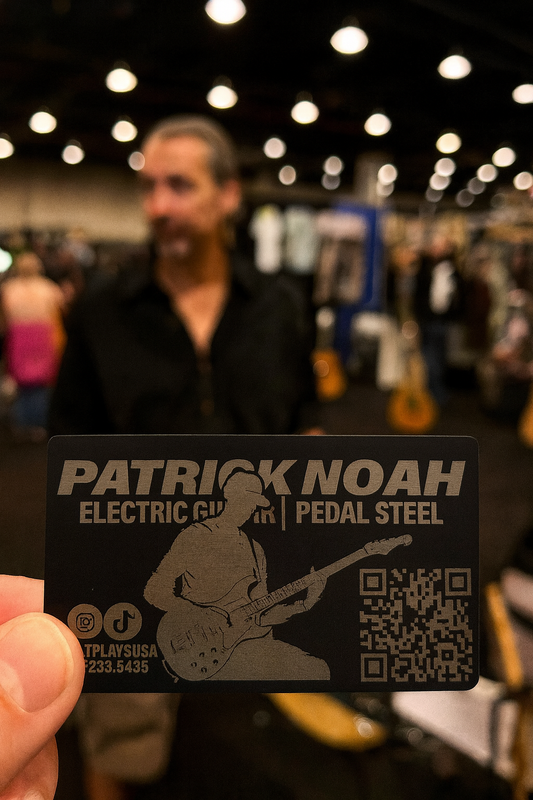 Person holding a laser engrave metal business card for guitarists, with custom photo, social handles, scannable QR code and personalized text, at a music event