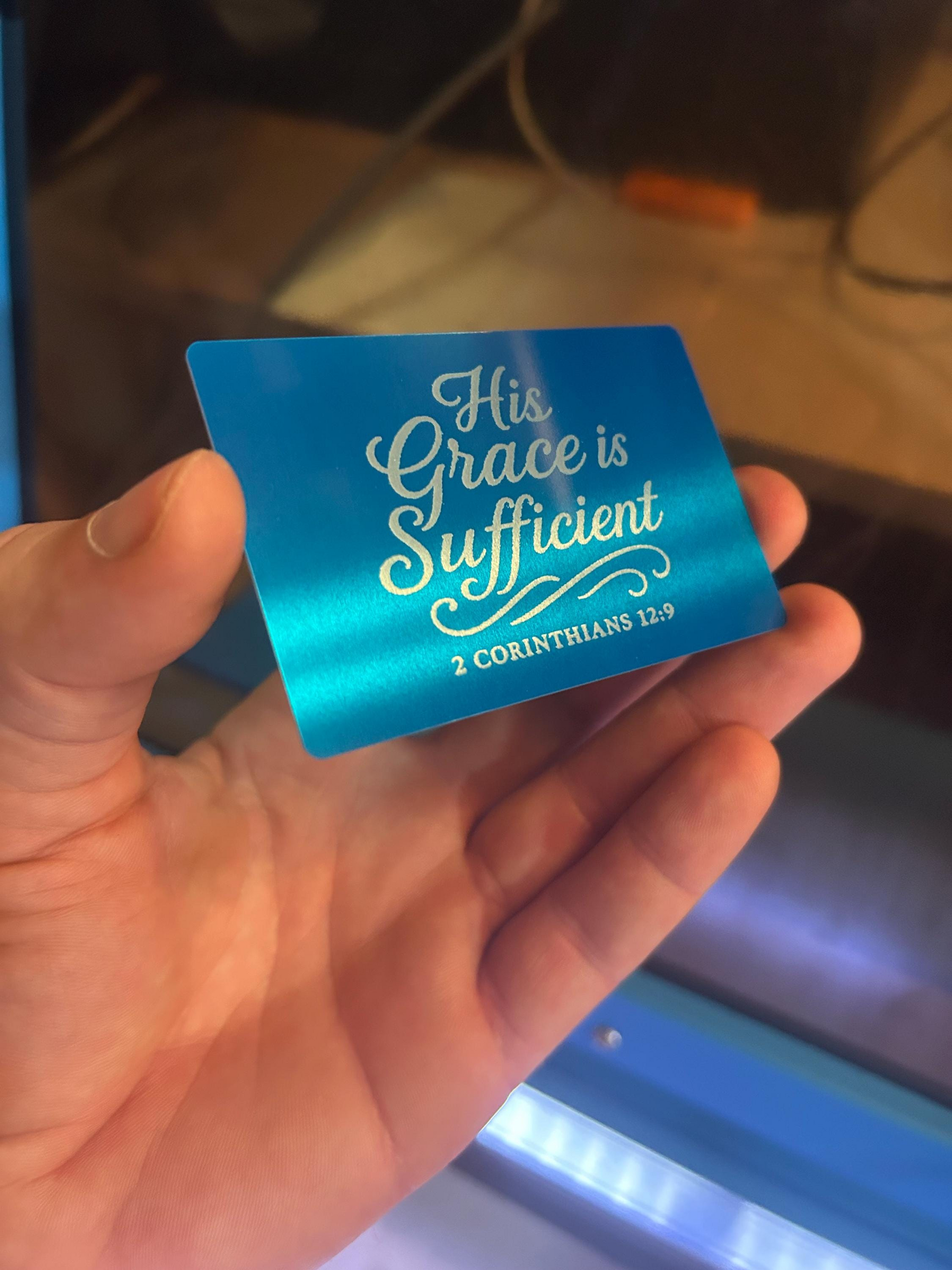Blue and Silver Metal Keepsake with laser engraved text that reads "His Grace Is Sufficient" in elegant typography, with a 2 Corinthians 12:9 Bible Verse Reference below