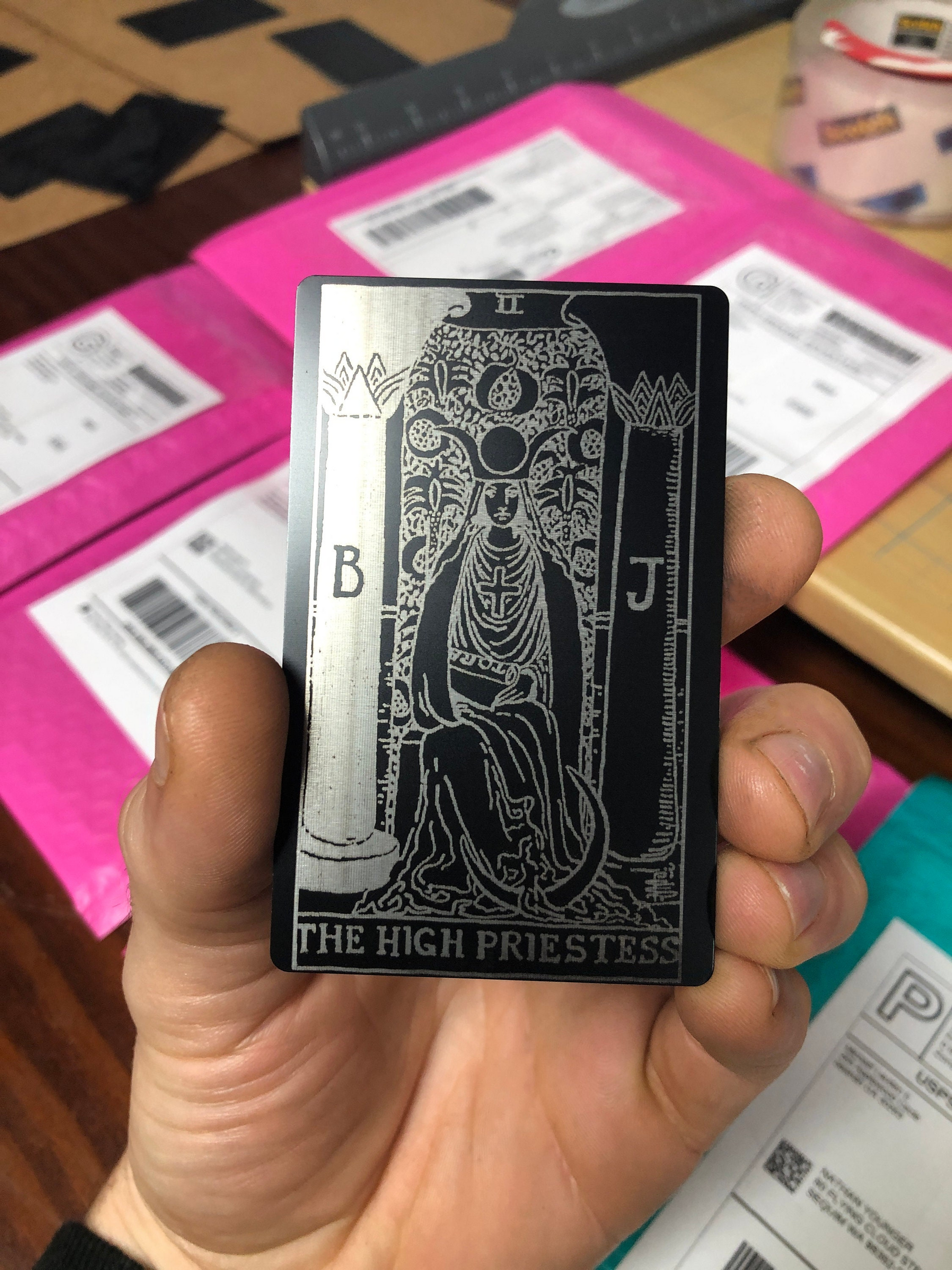 Tarot Card with metal 'The High Priestess' design held by a hand, with a blurred background