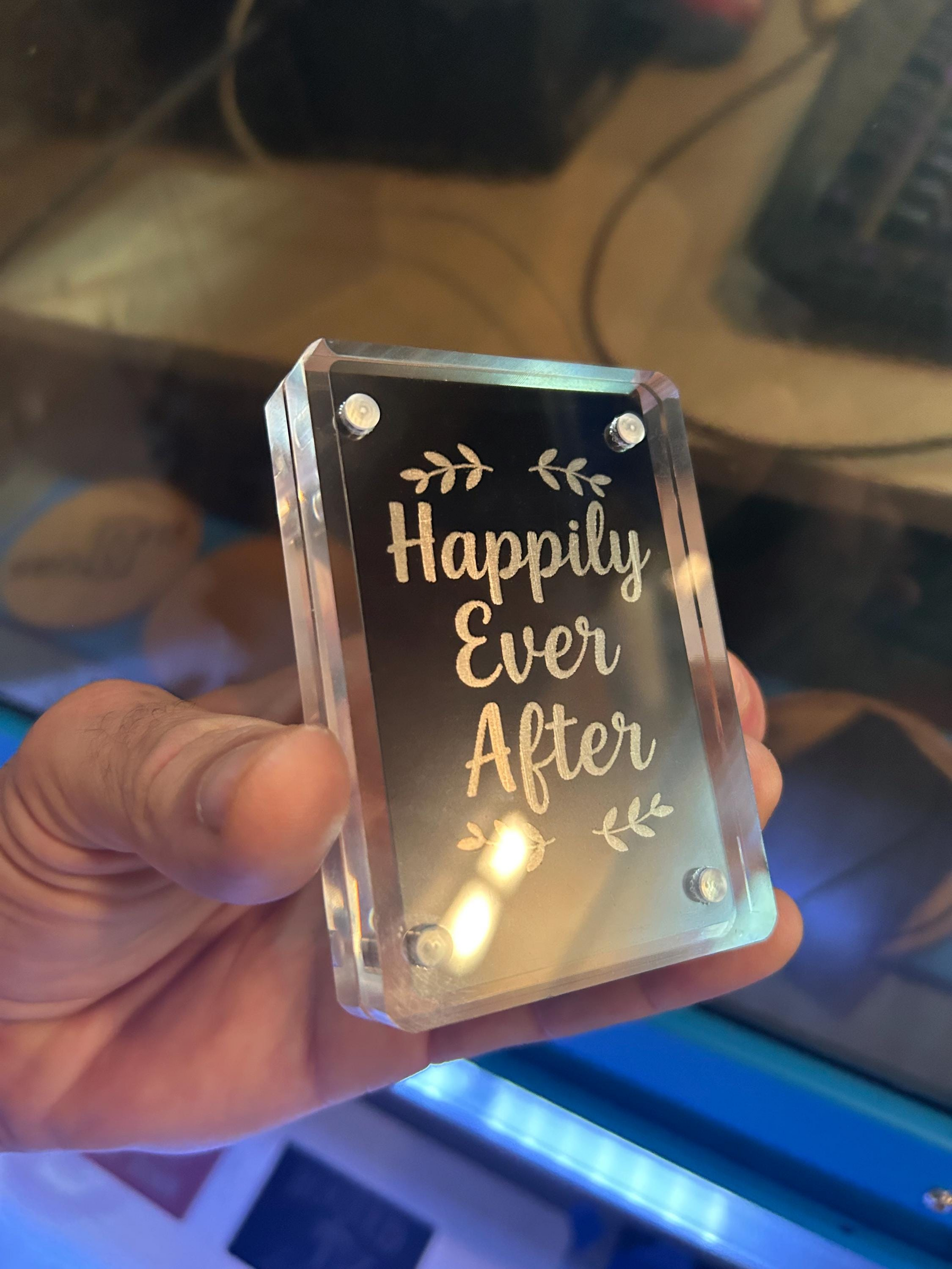 Angled shot of custom black/silver engraved couples card featuring “Happily Ever After” script art