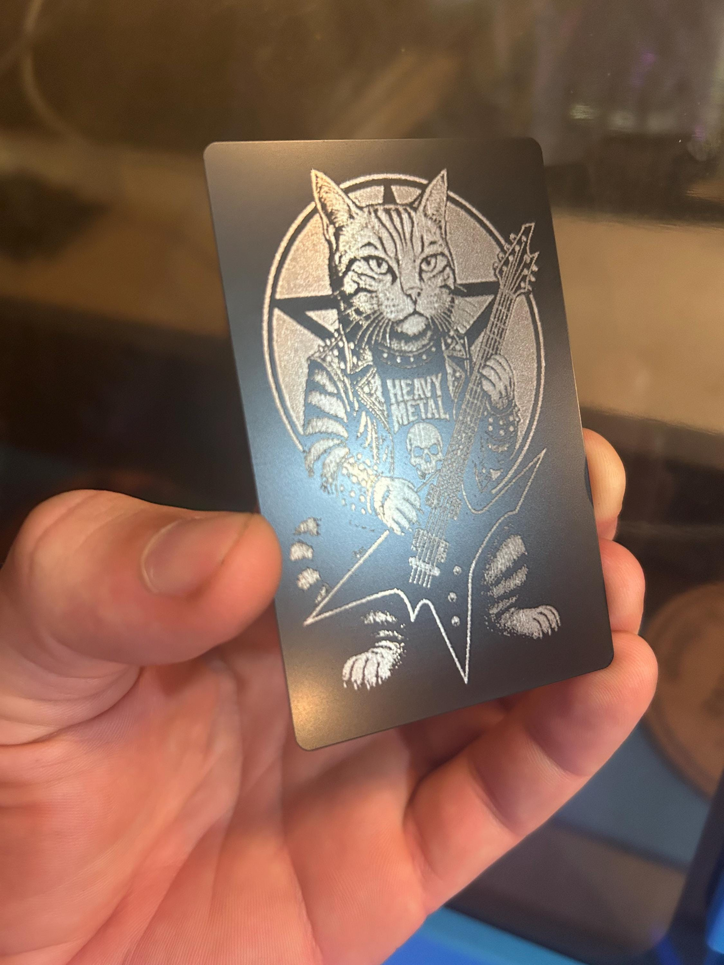 Black and silver metal novelty card with a heavy metal cat in leather jacket and studs, playing extended range guitar design held in a hand.