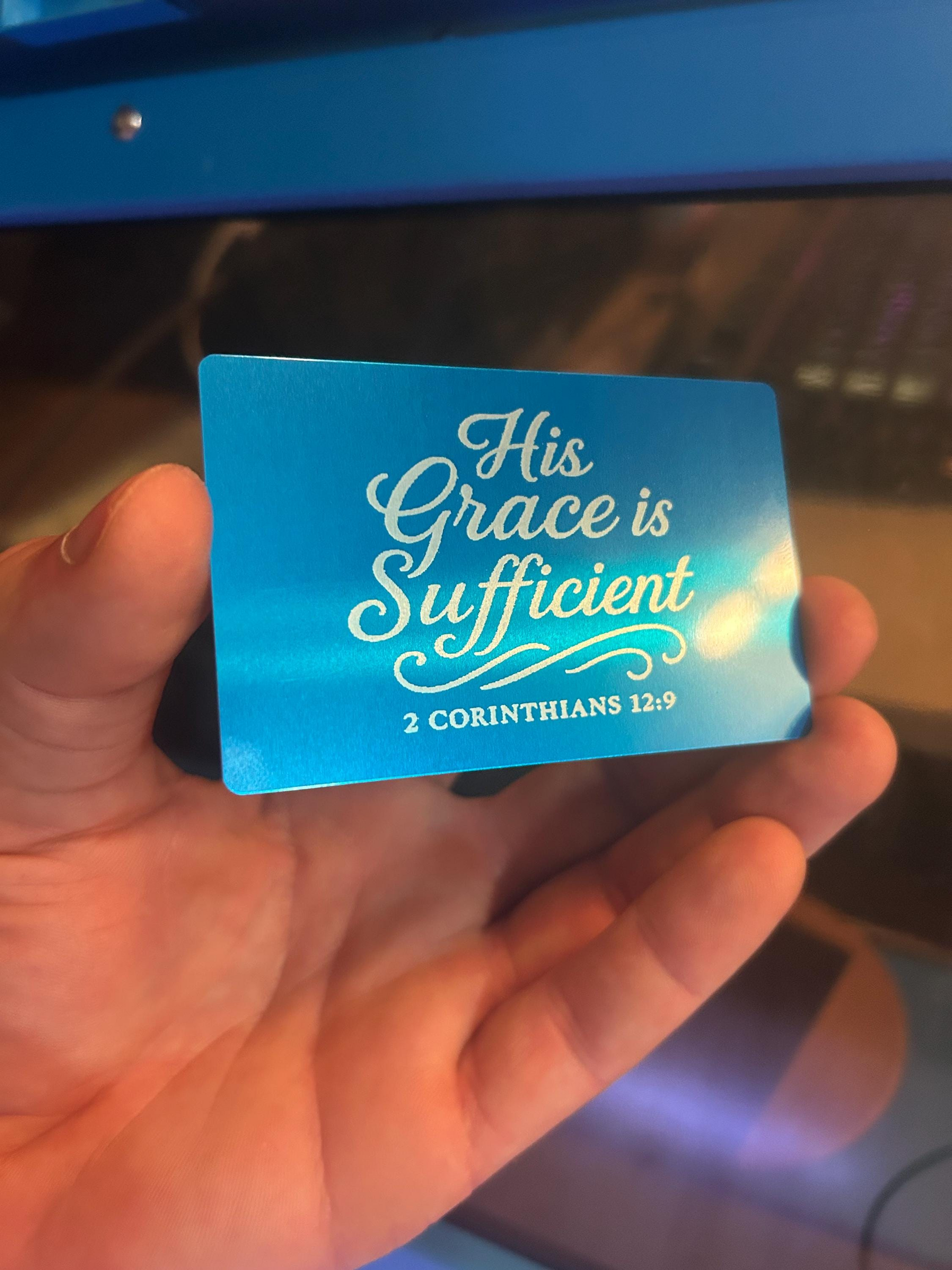 Blue card with 'His Grace is Sufficient' text held by a hand
