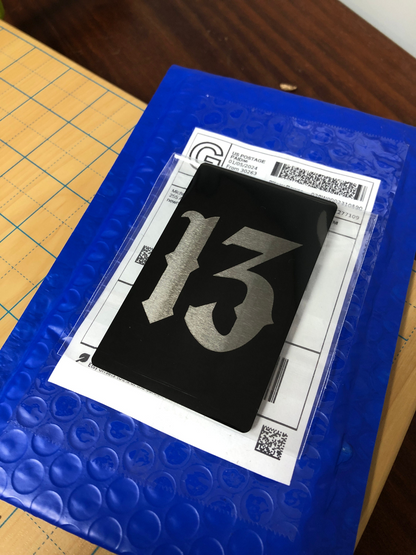 Number 13 laser engraved gothic keepsake gift card on a blue bubble wrap with a clear plastic sheet