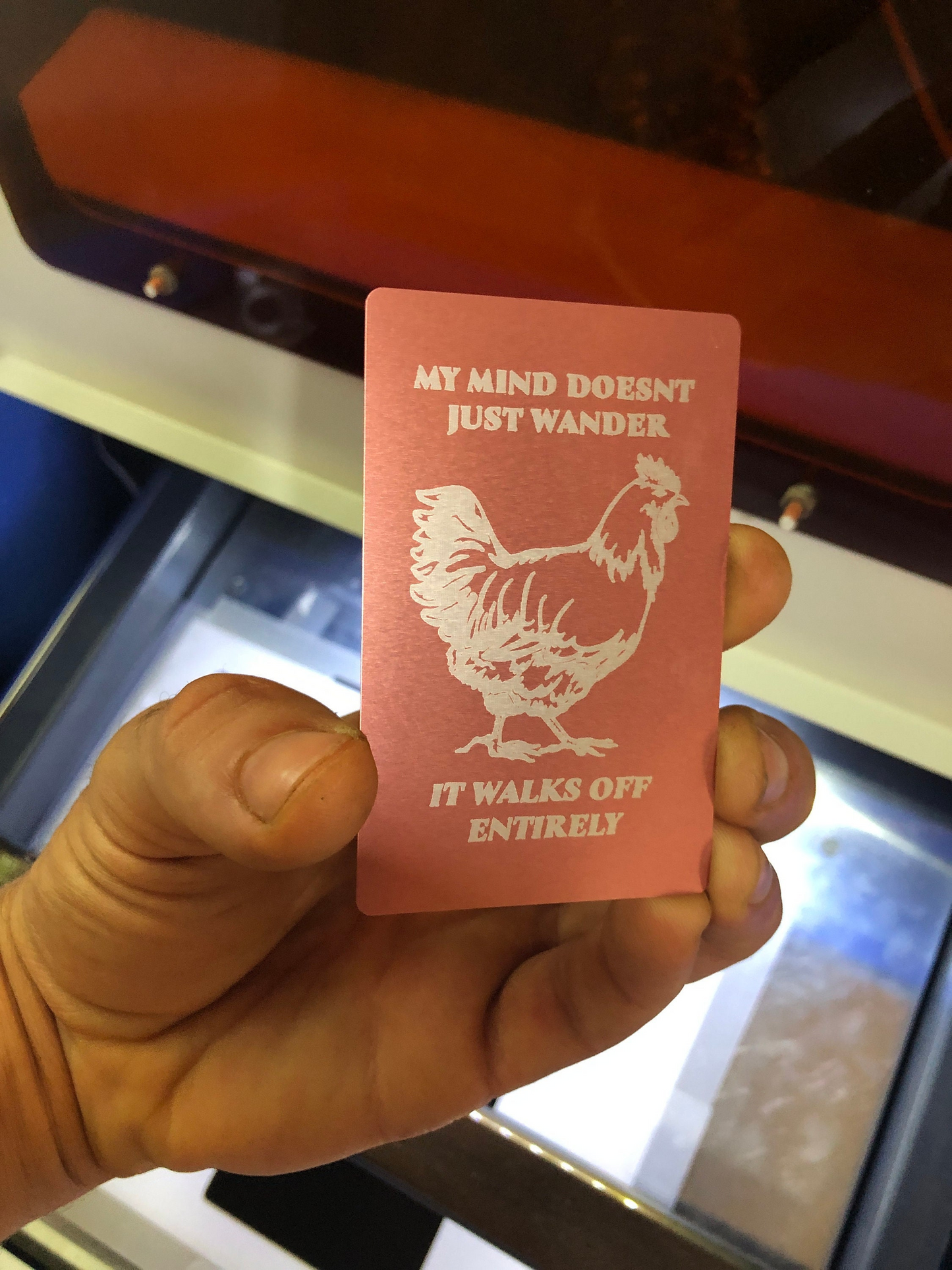 Hand holding a laser engraved metal rose gold farmhouse decor placard with a rooster illustration and funny gag gift text.