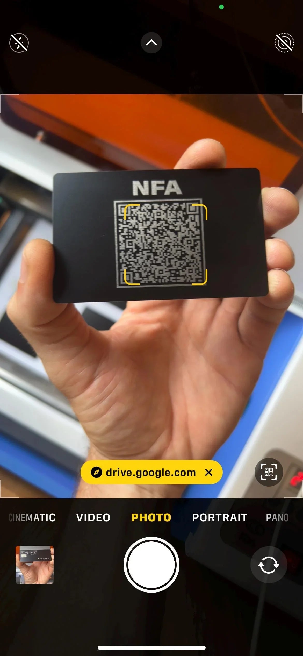 Hand holding a black card with QR code, screenshot/example of how Camera App scans QR code