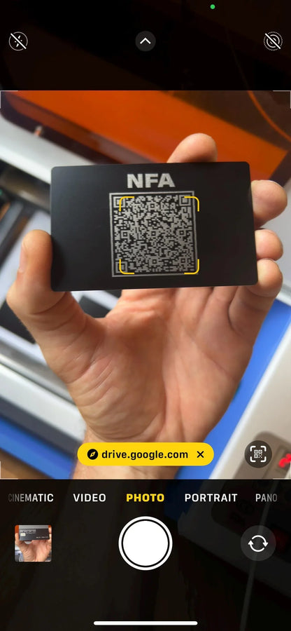 Hand holding a black card with QR code, screenshot/example of how Camera App scans QR code