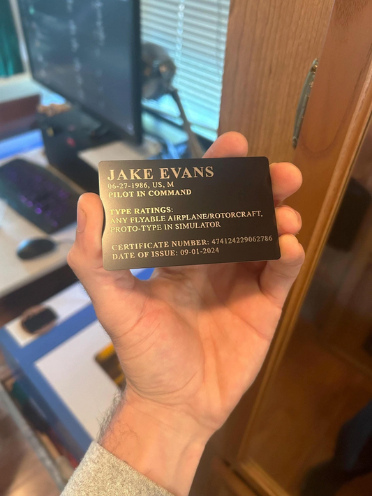 Hand holding a pilot's identification card with custom information engraved on it, in an indoor setting.