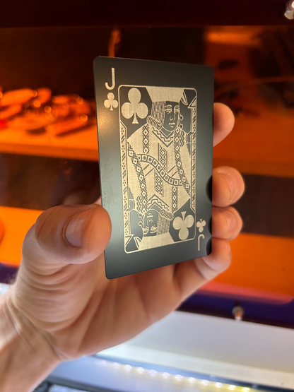 Hand holding a black and silver metal poker card with a blurred background