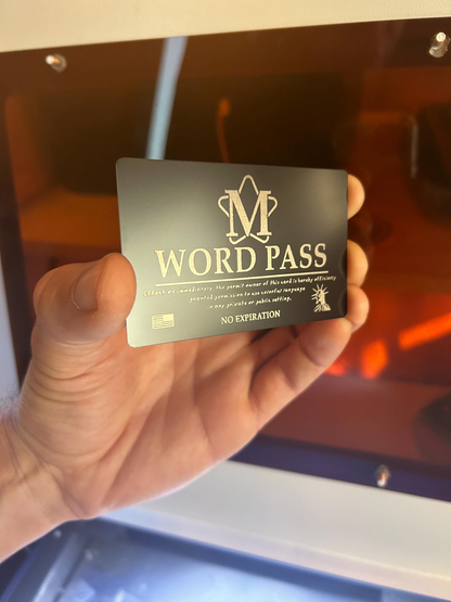 Hand holding a laser engraved metal 'M WORD PASS' card with a blurred machine background