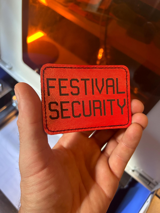 Red 'Festival Security' leather patch held in a hand with a blurred background