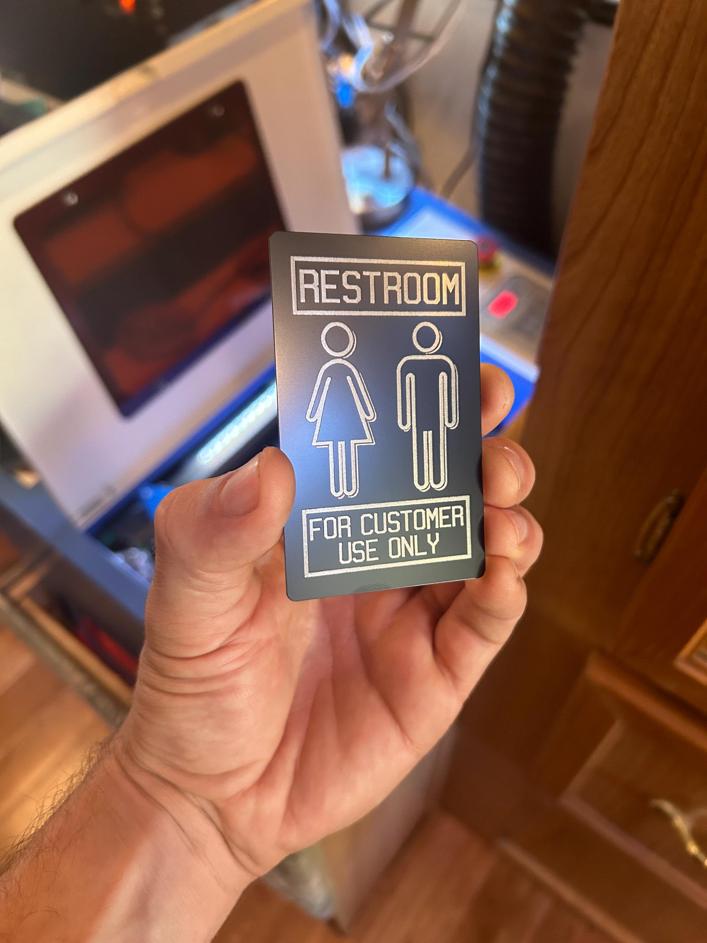Hand holding a restroom sign with symbols for customer use only.