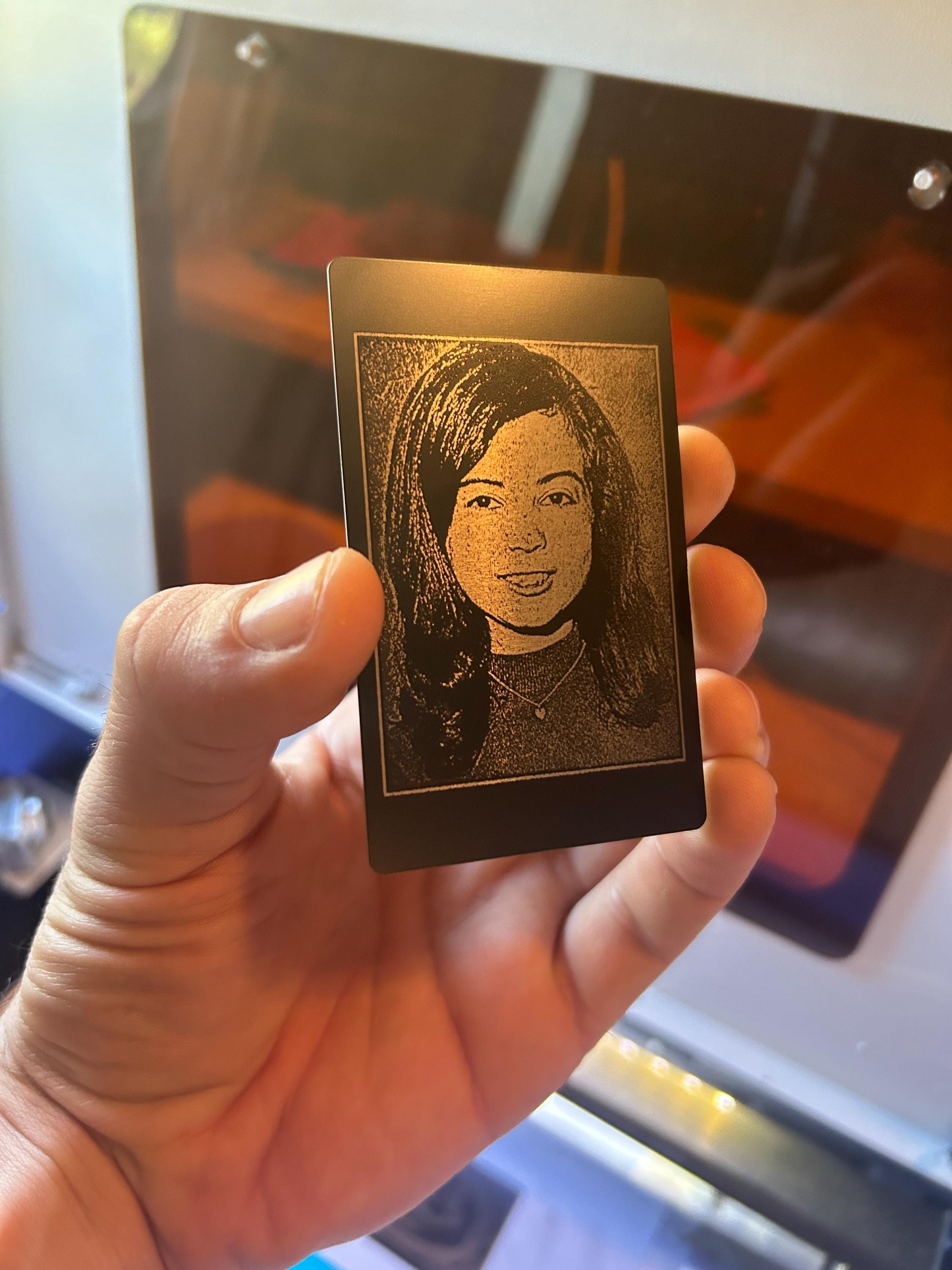 Hand holding a small rectangular metal plate with a engraved portrait of a woman.