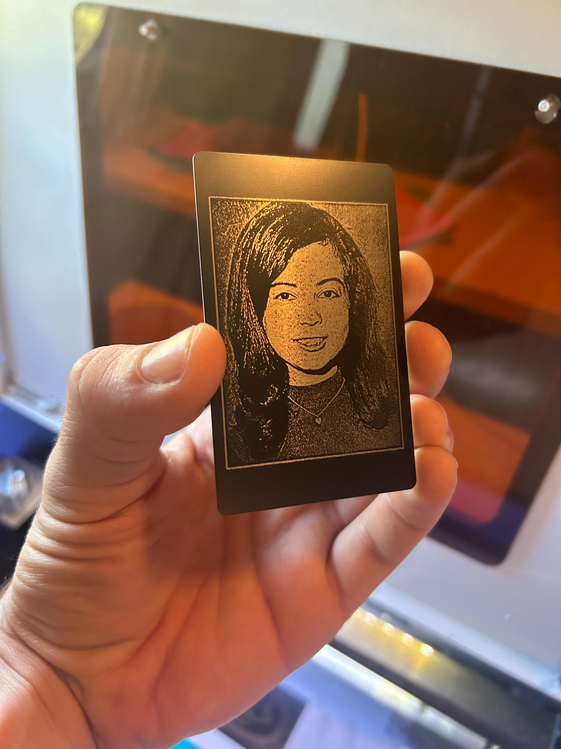 Hand holding a small rectangular metal plate with a engraved portrait of a woman.