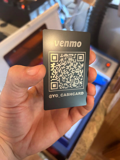 Hand holding a customized Venmo cash card with a QR code on a blurred background